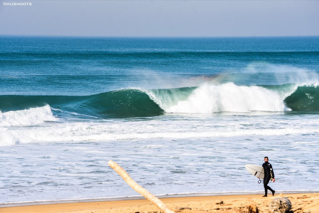 Une vague magnifique casse derrière lorsque un surfeur qui marche sur la plage d'Hossegor.